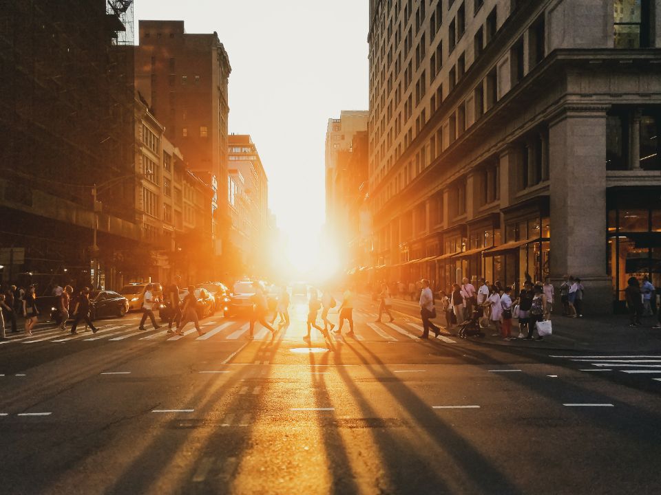 Een foto waar je de zon ziet tussen gebouwen in de stad.