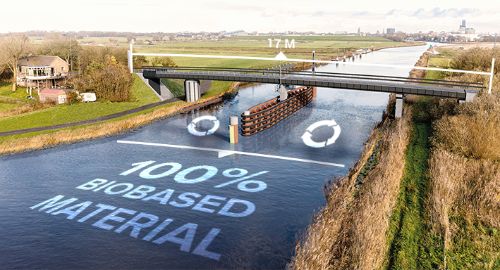 Image of the biobased bicycle bridge: Ritsumasyl. The length of the bridge is indicated and in the water the text: '100 % biobased material' is written.