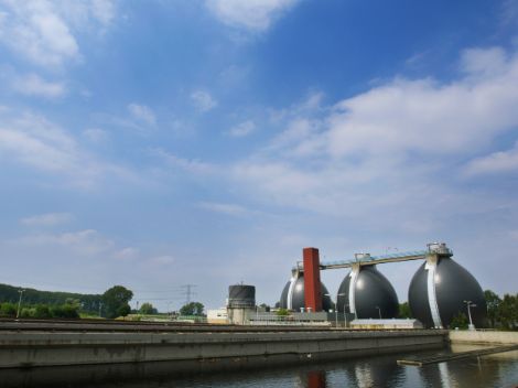 Foto van de energiefabriek in Hengelo met drie grote tanks en een water bassin. 