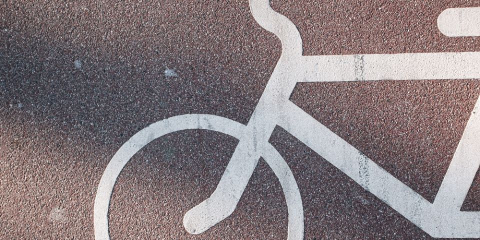 A photo of a pink cycle path with lines of a bicycle in white.<br/>
